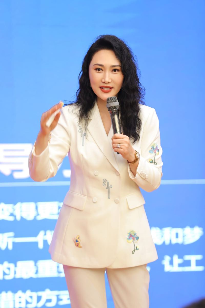 爱华老师身着白色西装手持话筒授课